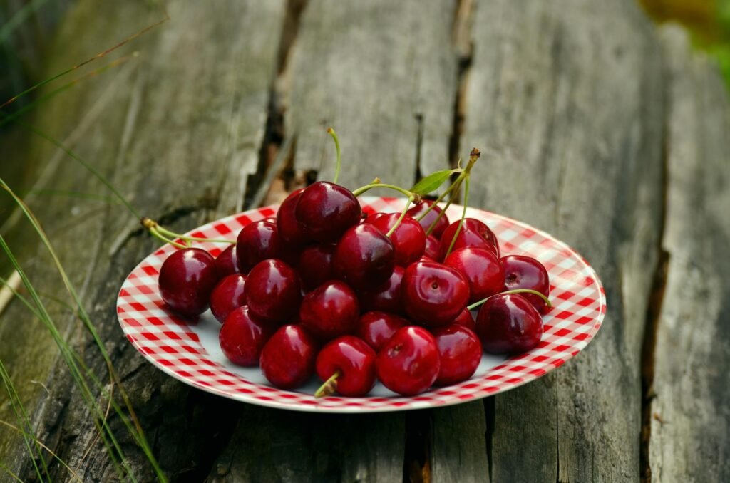 A vibrant display of red cherries on a patterned plate outdoors, perfect for summer themes.