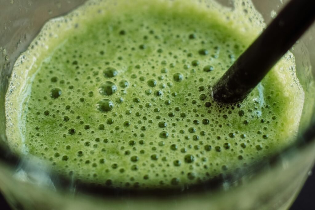 Close-up of a frothy green smoothie with bubbles and a straw for a fresh start.