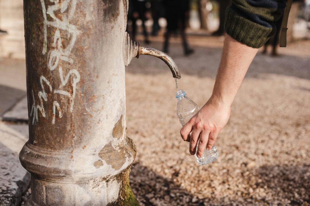 A person fills a plastic bottle from an old water fountain in Rome, Italy.