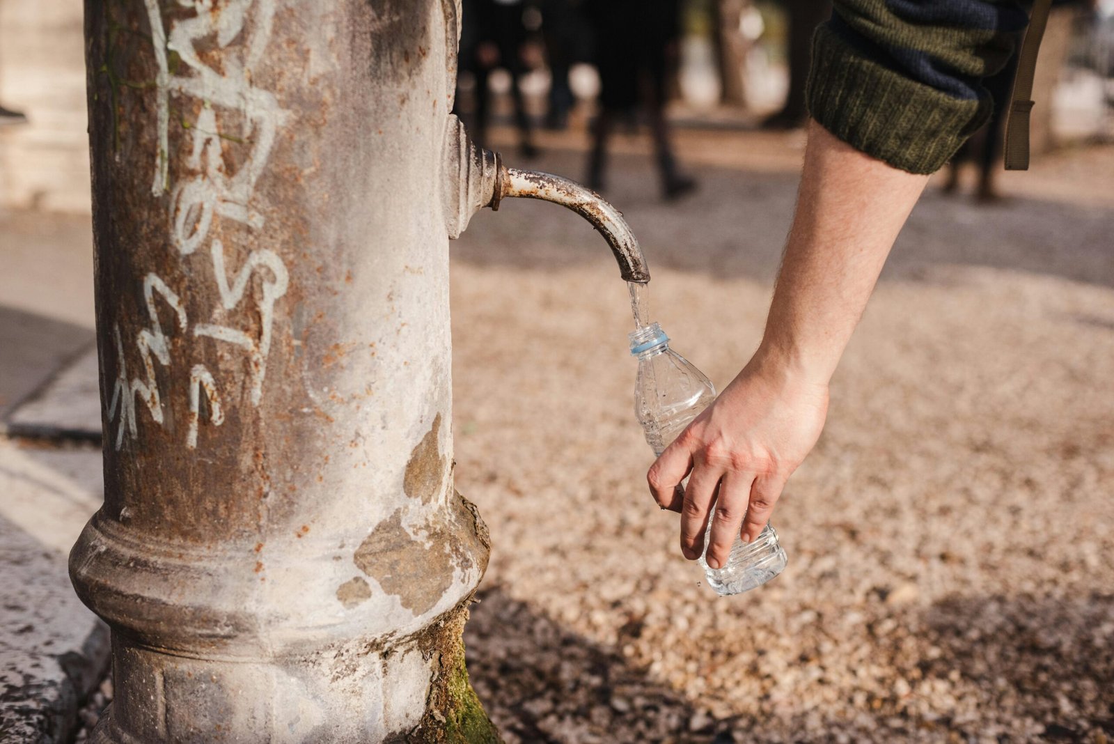 A person fills a plastic bottle from an old water fountain in Rome, Italy.